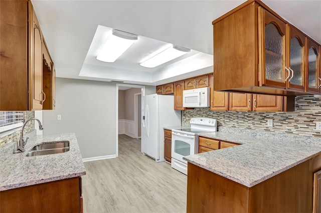 kitchen with sink, light stone counters, light hardwood / wood-style flooring, kitchen peninsula, and white appliances