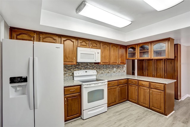 kitchen with light hardwood / wood-style floors, white appliances, kitchen peninsula, and tasteful backsplash