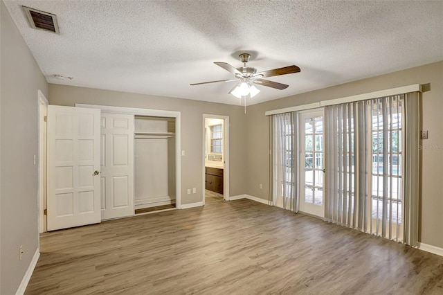 unfurnished bedroom featuring connected bathroom, ceiling fan, light hardwood / wood-style floors, and a textured ceiling