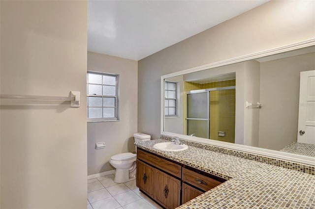 bathroom featuring tile patterned flooring, vanity, toilet, and a shower with shower door