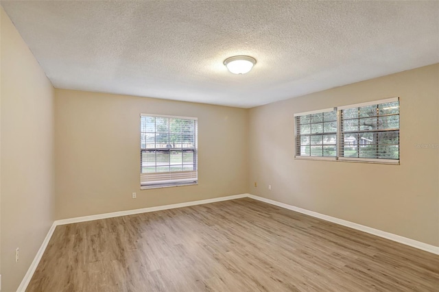 unfurnished room with wood-type flooring and a textured ceiling