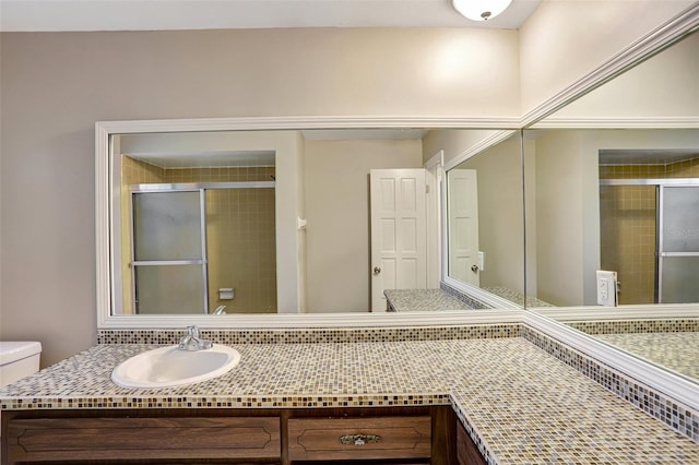 bathroom with vanity, toilet, and a shower with door