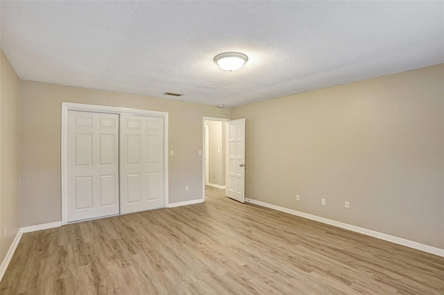 unfurnished bedroom featuring a textured ceiling, light hardwood / wood-style floors, and a closet