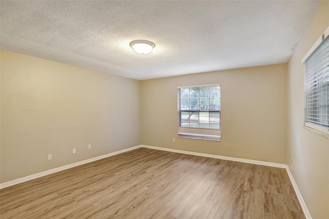 empty room with light wood-type flooring and a textured ceiling