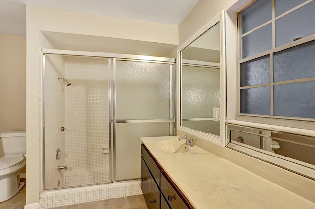 bathroom with tile patterned floors, vanity, toilet, and a shower with shower door