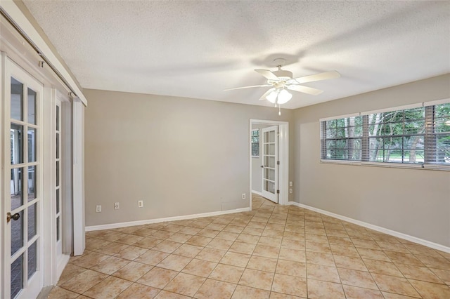 empty room featuring ceiling fan, french doors, light tile patterned floors, and a textured ceiling