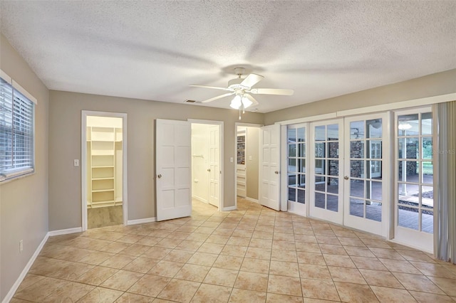 spare room with ceiling fan, french doors, light tile patterned flooring, and a textured ceiling