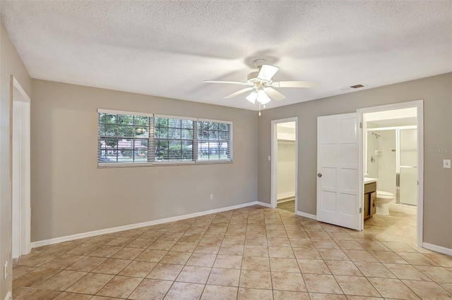 unfurnished bedroom with a textured ceiling, a closet, a spacious closet, and ceiling fan