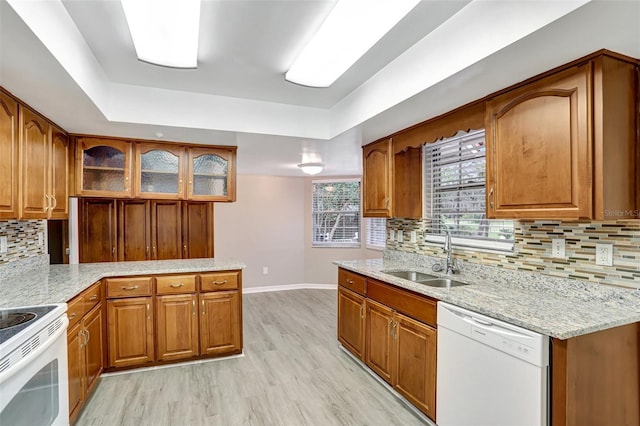 kitchen with light stone countertops, tasteful backsplash, white appliances, sink, and light hardwood / wood-style flooring