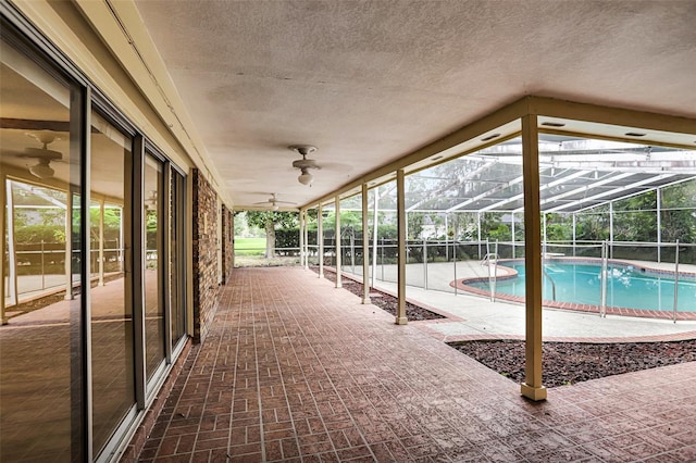 view of pool with a patio area, ceiling fan, and glass enclosure