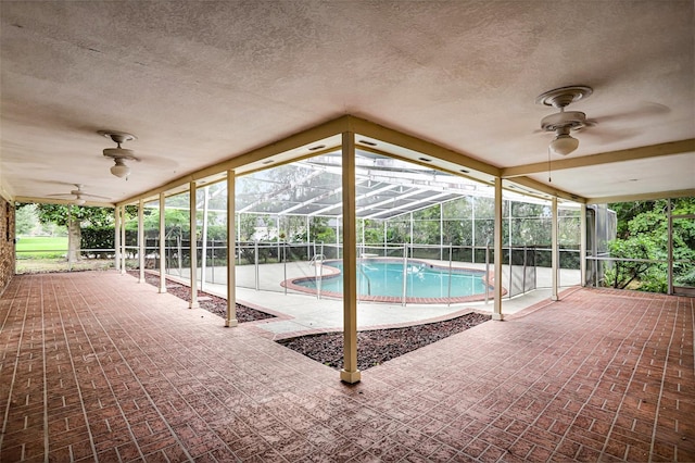 view of swimming pool featuring a patio area, ceiling fan, and glass enclosure