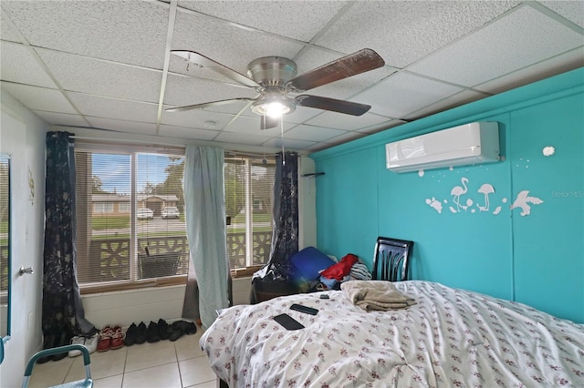 tiled bedroom featuring a wall unit AC, a paneled ceiling, and ceiling fan