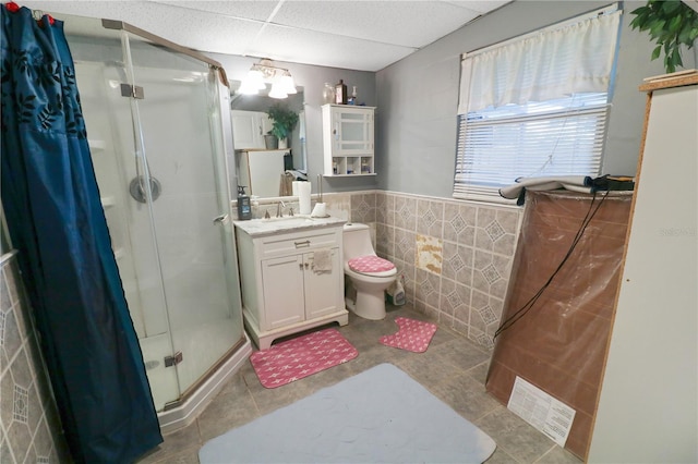 bathroom featuring a paneled ceiling, vanity, tile patterned floors, tile walls, and walk in shower