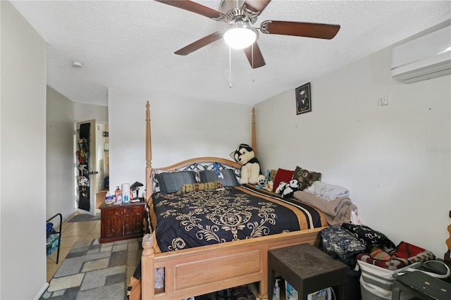 tiled bedroom featuring a wall mounted air conditioner, ceiling fan, and a textured ceiling