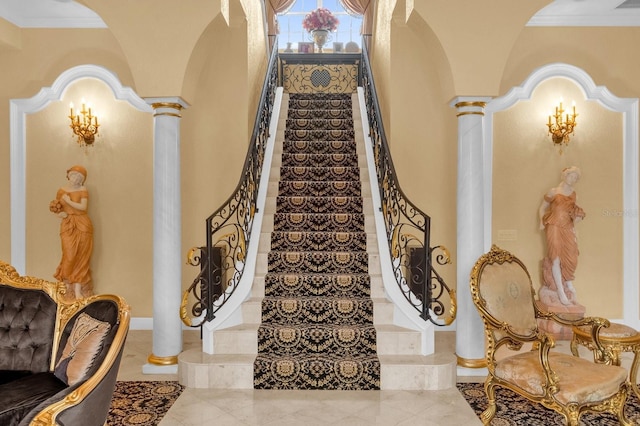 staircase featuring ornate columns and crown molding