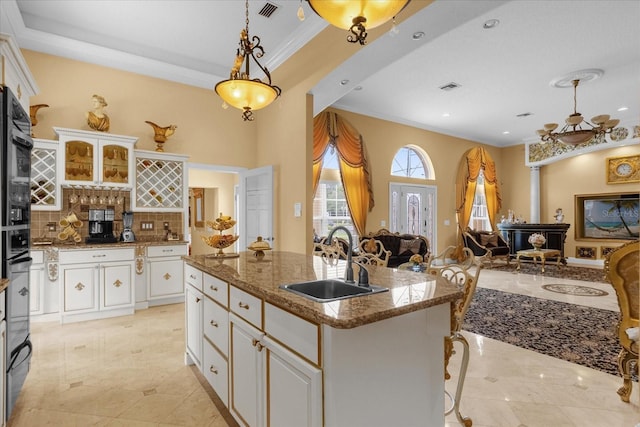 kitchen with a center island with sink, white cabinetry, and sink