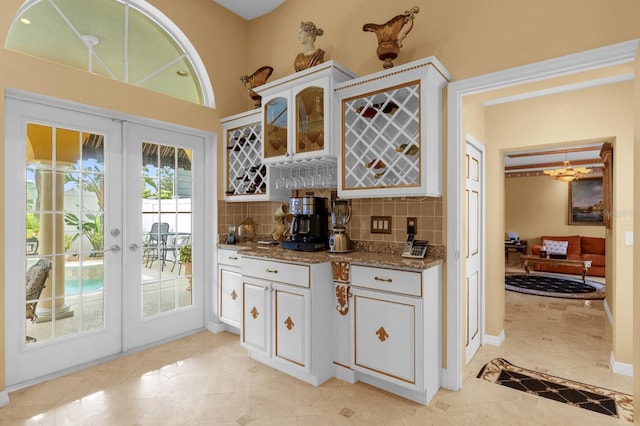 bar with backsplash, french doors, light tile patterned floors, stone countertops, and white cabinetry