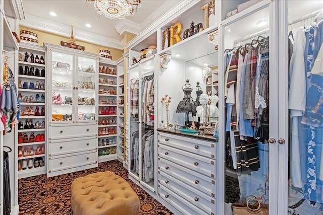 walk in closet with dark colored carpet and an inviting chandelier