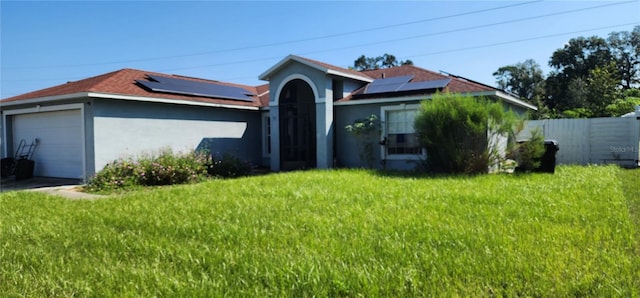 view of front facade with a garage, a front yard, and solar panels