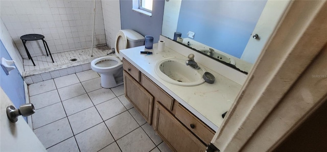 bathroom featuring tile patterned floors, vanity, a tile shower, and toilet