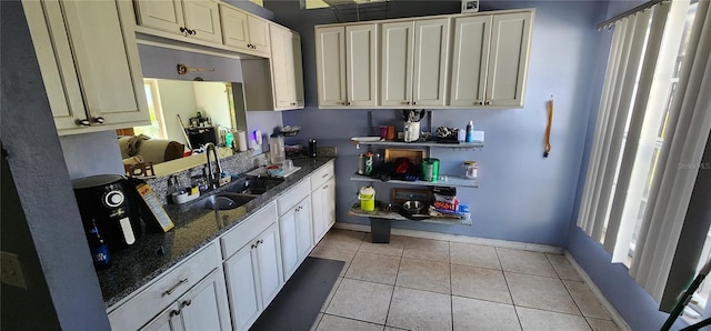 kitchen featuring sink, light tile patterned floors, and dark stone counters