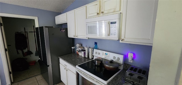 kitchen with lofted ceiling, a textured ceiling, electric range oven, white cabinetry, and stainless steel refrigerator