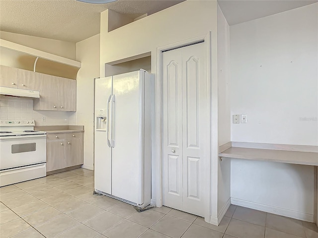 kitchen featuring a textured ceiling, lofted ceiling, light tile patterned floors, and white appliances