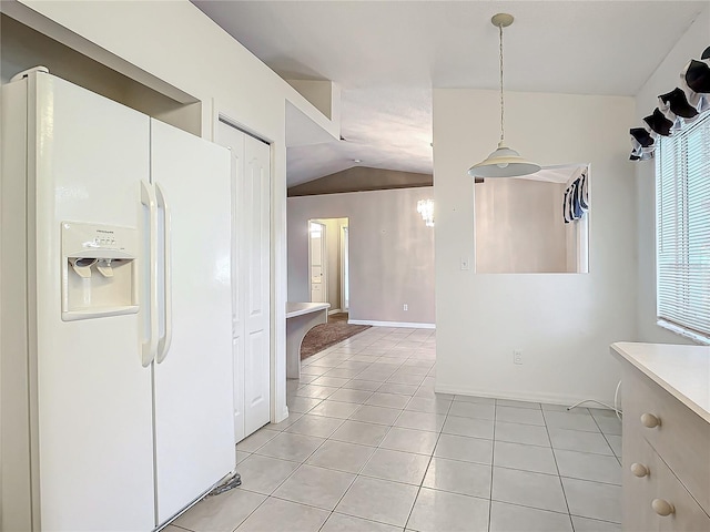 kitchen with pendant lighting, light tile patterned flooring, white fridge with ice dispenser, and vaulted ceiling