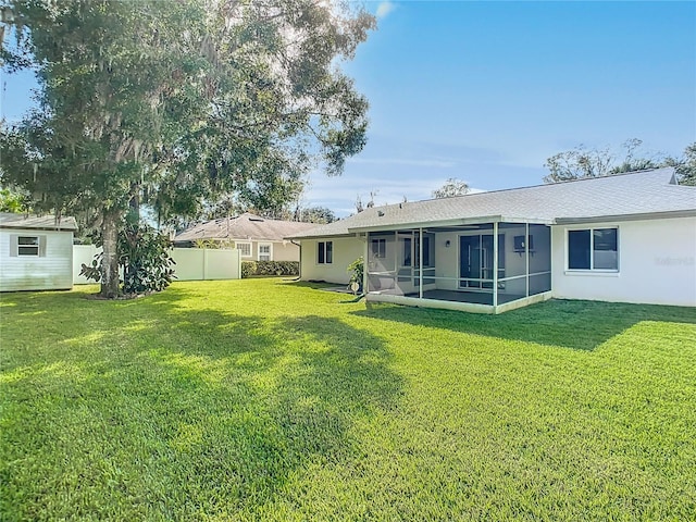 rear view of house with a sunroom and a lawn