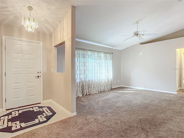 carpeted entrance foyer with ceiling fan with notable chandelier, a textured ceiling, and vaulted ceiling