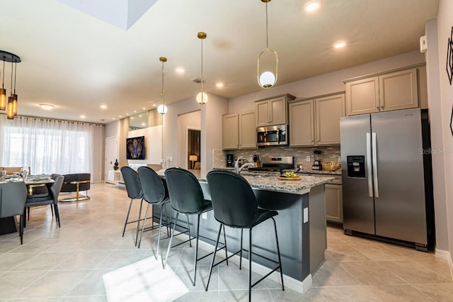 kitchen featuring backsplash, light stone counters, pendant lighting, and stainless steel appliances