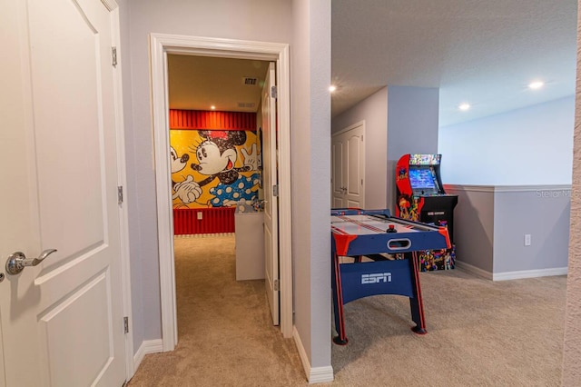 recreation room with light colored carpet and a textured ceiling