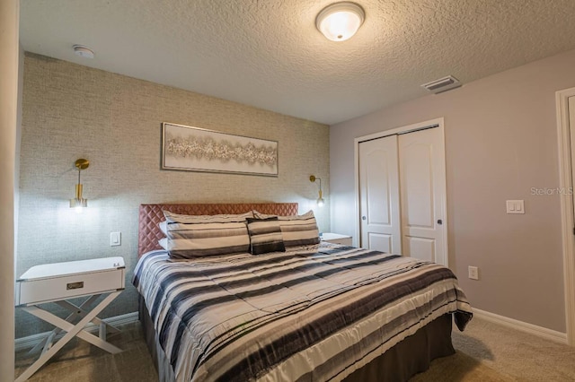 bedroom with a textured ceiling, carpet floors, and a closet