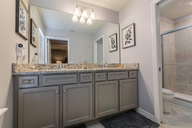 bathroom featuring tile patterned floors, vanity, toilet, and a shower with door