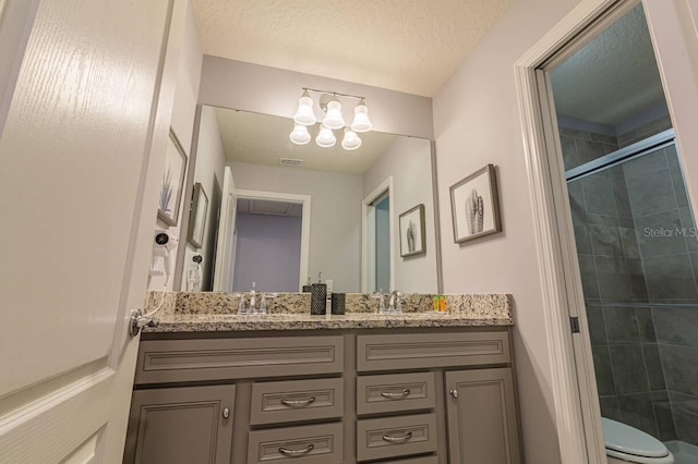 bathroom with vanity, a shower with shower door, a textured ceiling, and toilet