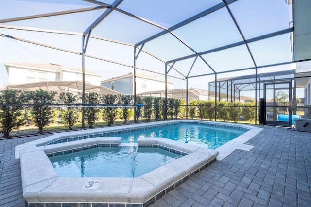 view of pool with glass enclosure, a patio area, and an in ground hot tub