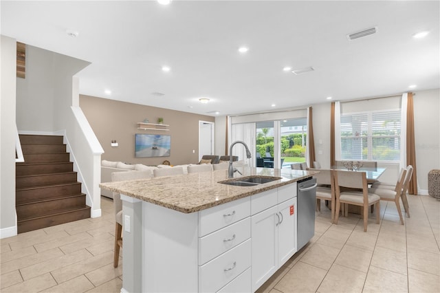 kitchen with sink, light stone counters, stainless steel dishwasher, a center island with sink, and white cabinets