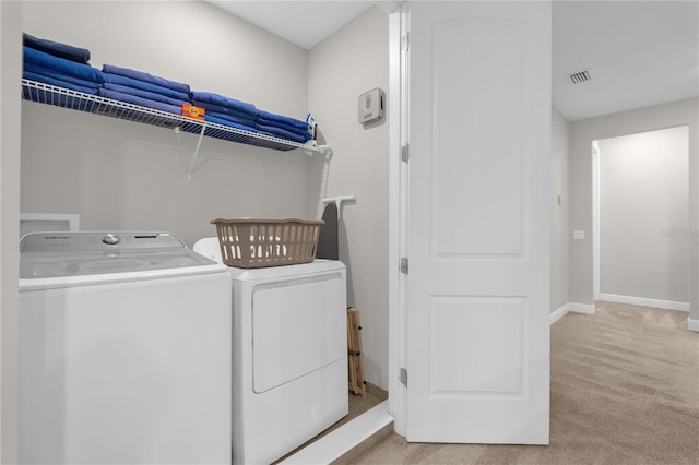 washroom with washing machine and clothes dryer and light carpet