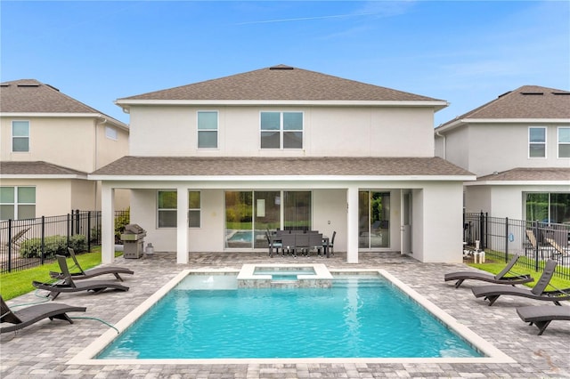 rear view of house featuring a swimming pool with hot tub and a patio area