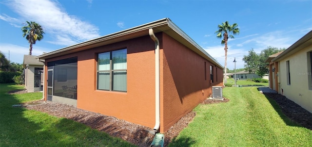 view of property exterior featuring a yard, central air condition unit, and a sunroom