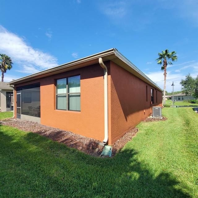 view of home's exterior with a lawn, a sunroom, and cooling unit