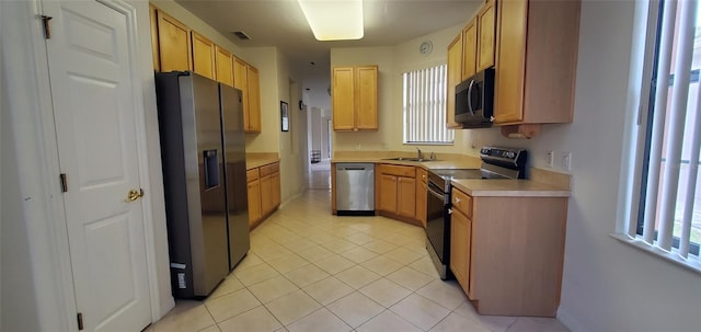 kitchen with sink, light tile patterned flooring, stainless steel appliances, and light brown cabinets