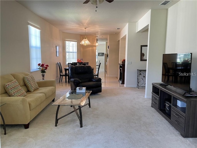 carpeted living room featuring ceiling fan with notable chandelier