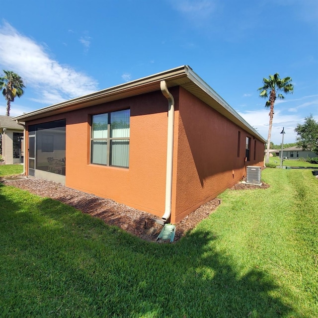 view of side of home with cooling unit and a yard