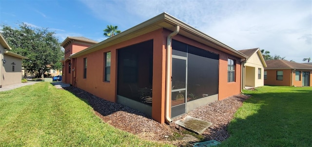 view of side of home featuring a sunroom and a lawn