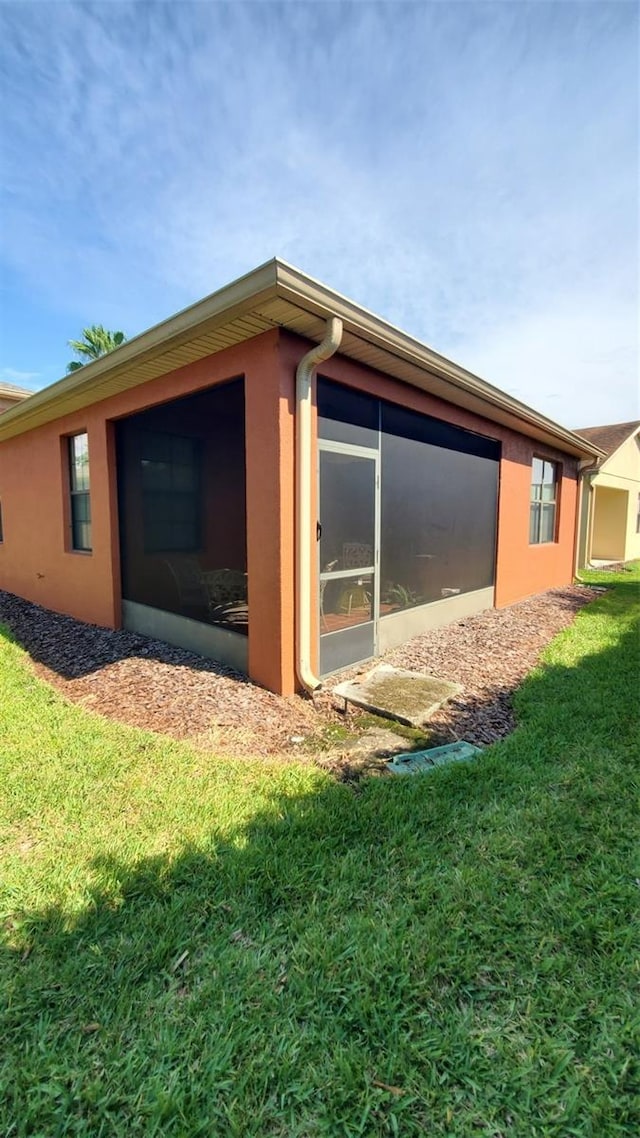 view of property exterior featuring a sunroom and a yard