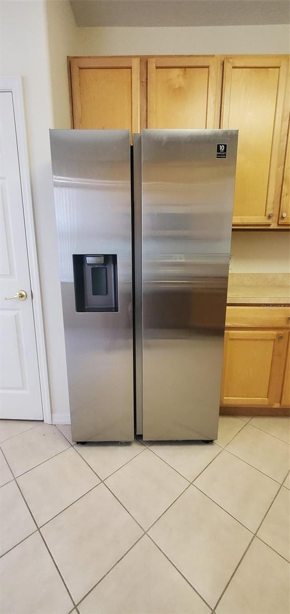 kitchen with light tile patterned flooring, stainless steel refrigerator with ice dispenser, and light brown cabinets