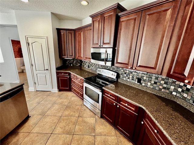 kitchen with stainless steel appliances, backsplash, dark stone countertops, a textured ceiling, and light tile patterned flooring