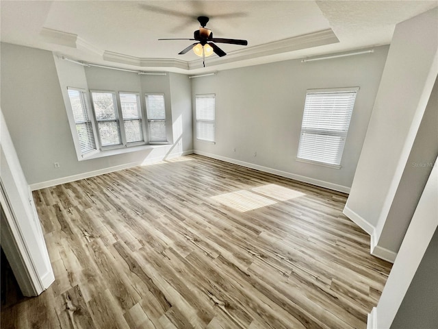 unfurnished living room with ornamental molding, a tray ceiling, ceiling fan, and light hardwood / wood-style floors