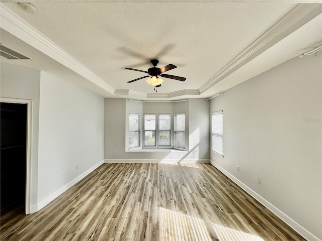 unfurnished living room with ornamental molding, a textured ceiling, a raised ceiling, ceiling fan, and light hardwood / wood-style floors